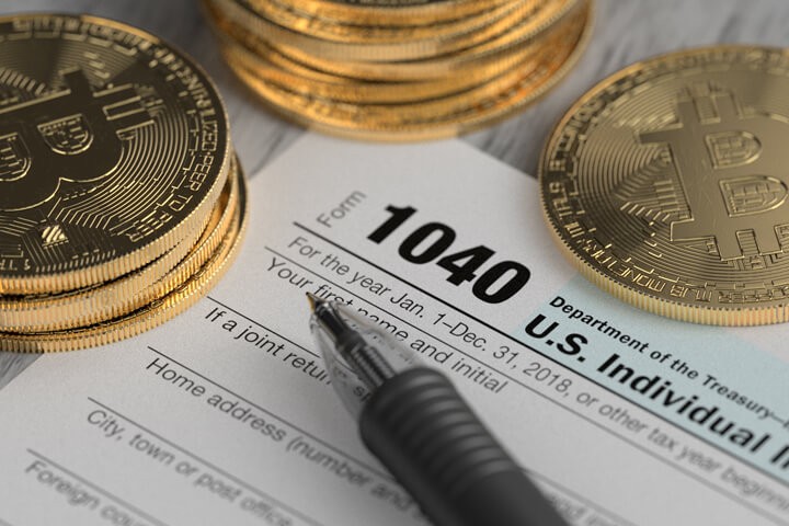 用黑色钢笔将黄金比特币放在 1040 年美国所得税表上